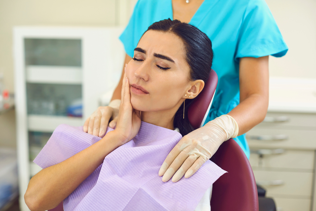 Young Woman Is Sitting in a Dentist's Chair and Suffering from Severe Toothache.